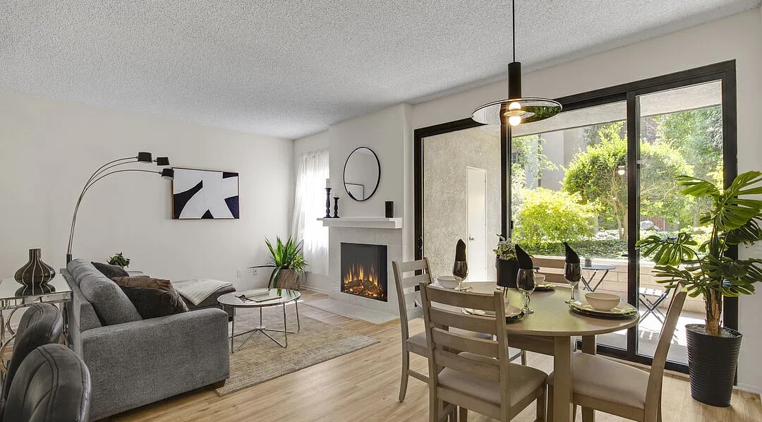 Staged condo living and dining area with fireplace and patio view