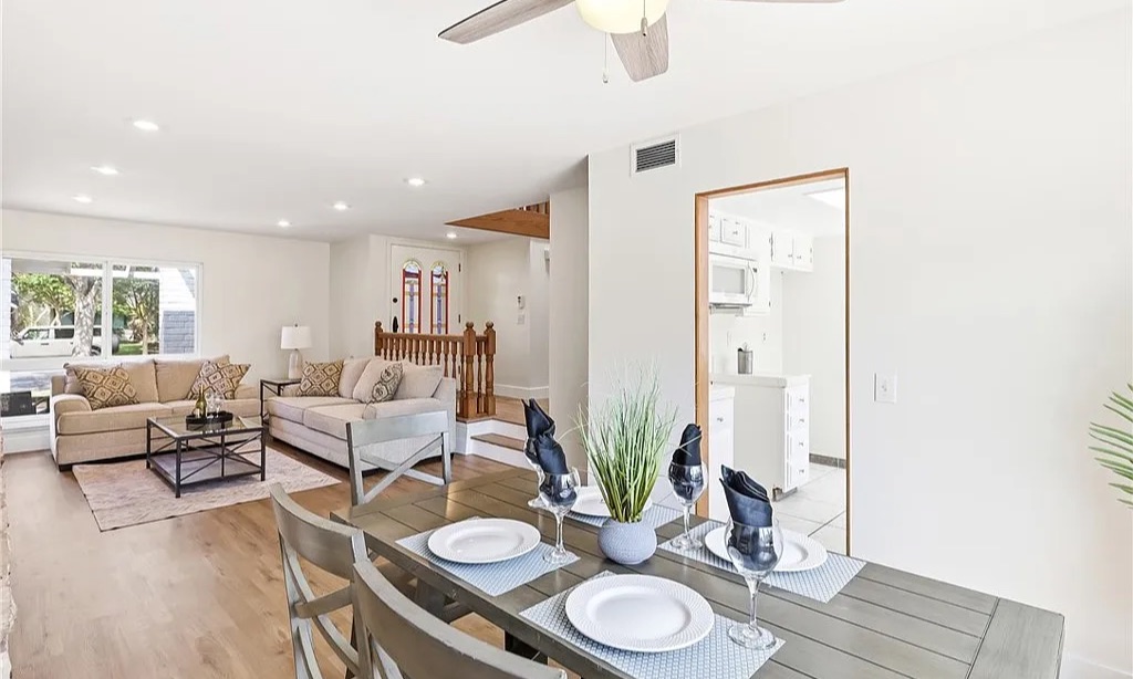 Staged dining table set for four, open to a family room
