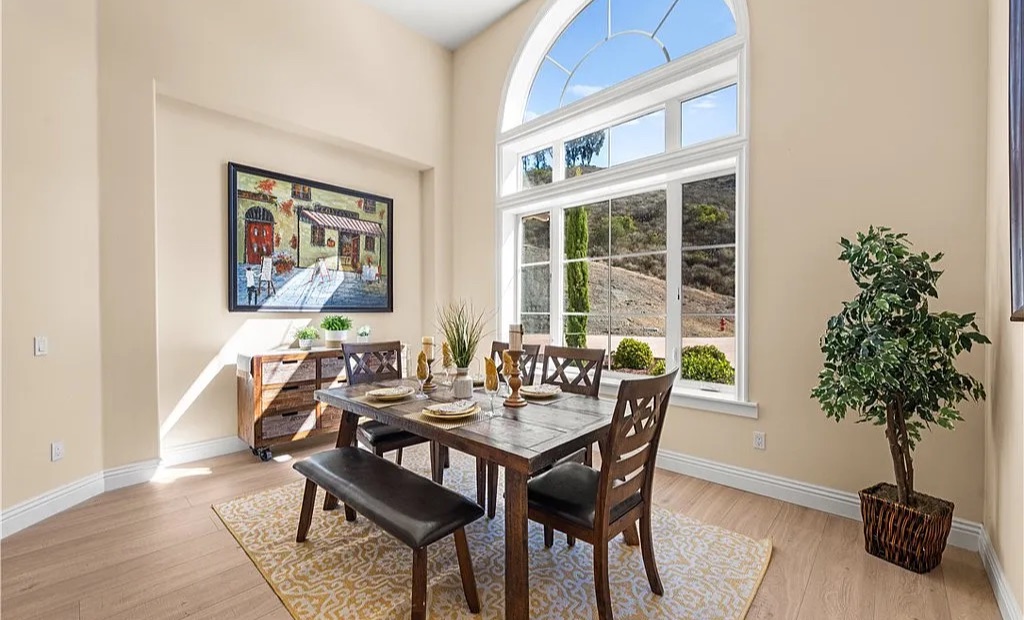 Staged dining room with farmhouse table beneath a two-story arched window