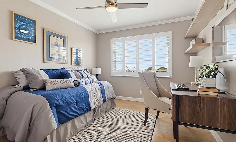Staged guest bedroom with desk workspace and coastal blue bedding