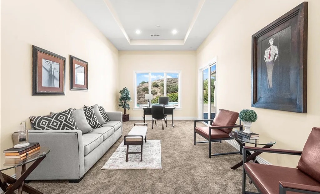 Staged home office and sitting area with desk, sofa, and leather chairs