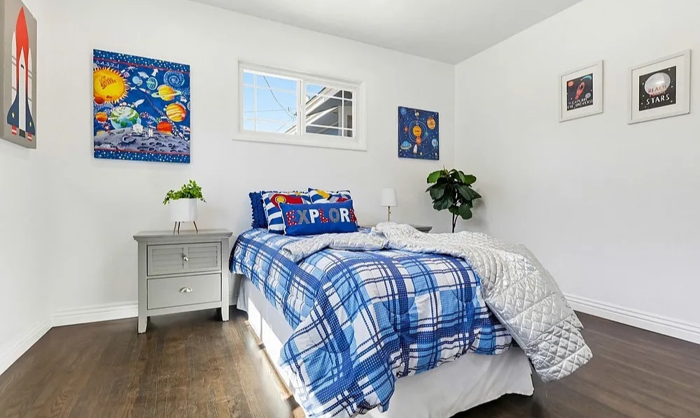 Staged kids' bedroom with space-themed art and blue plaid bedding