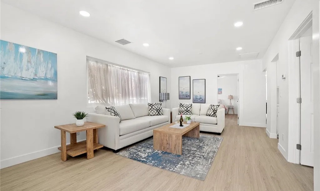 Staged living room with white sofas and a blue area rug