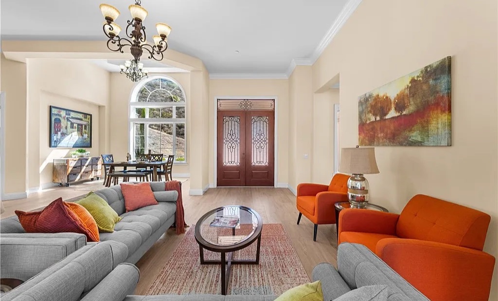 Staged living room and entry with gray sectionals and bold orange accent chairs