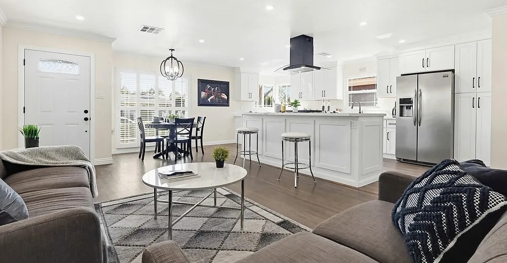 Staged open-concept living room and white kitchen with island seating