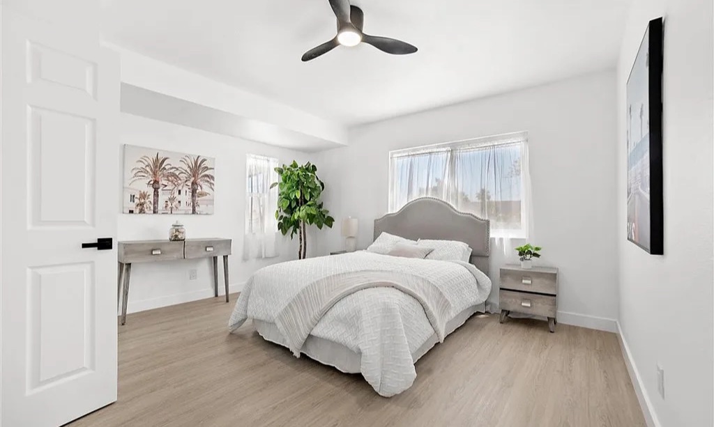 Staged primary bedroom in light neutrals with upholstered headboard